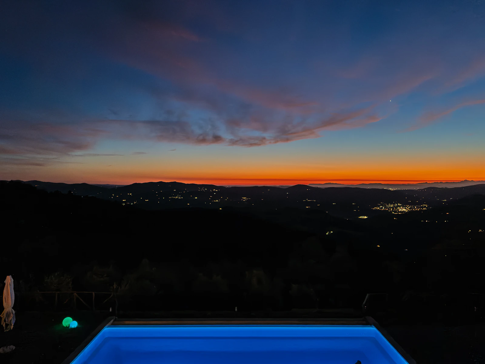 A pool glowing at dusk above a valley of distant lights